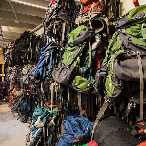 A wall of gently-worn hiking backpacks within an OEN gear library.
