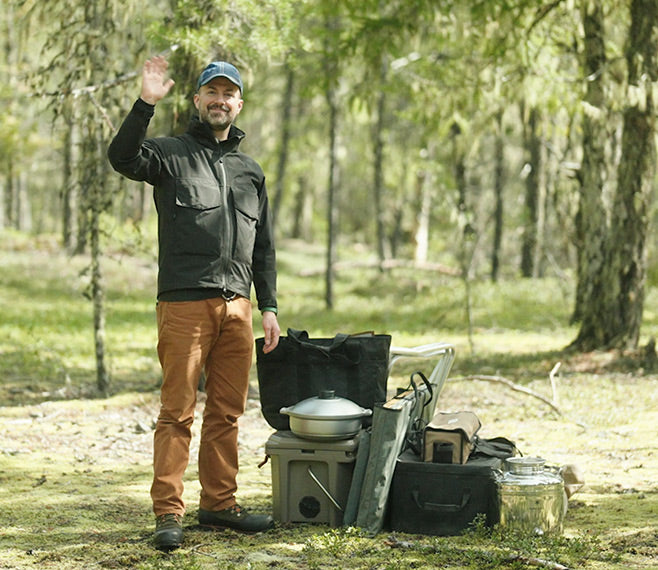 Snow Peak Beverage Director Jim Meehan stands in the forest with camping gear.